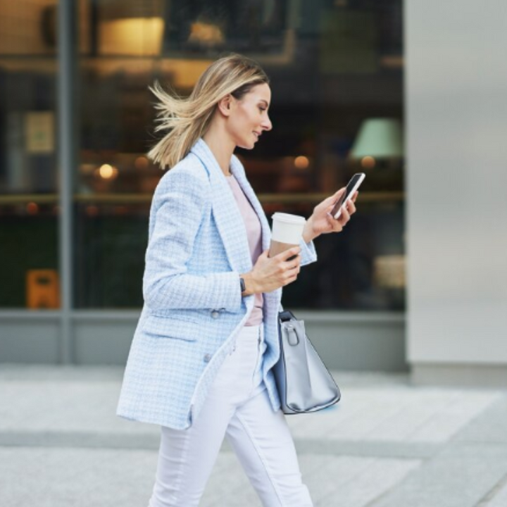 Na imagem vemos uma mulher usando terninho (blazer), ela é branca, ruiva e está sentada. As roupas dela representam a tendência Quiet Luxury